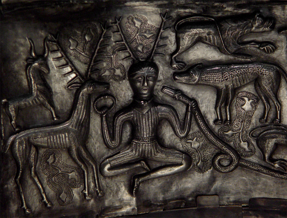 Detail of the antlered, cross-legged figure on the Gundestrup Cauldron, holding a torc and a ram-horned serpent, flanked by a stag and other animals