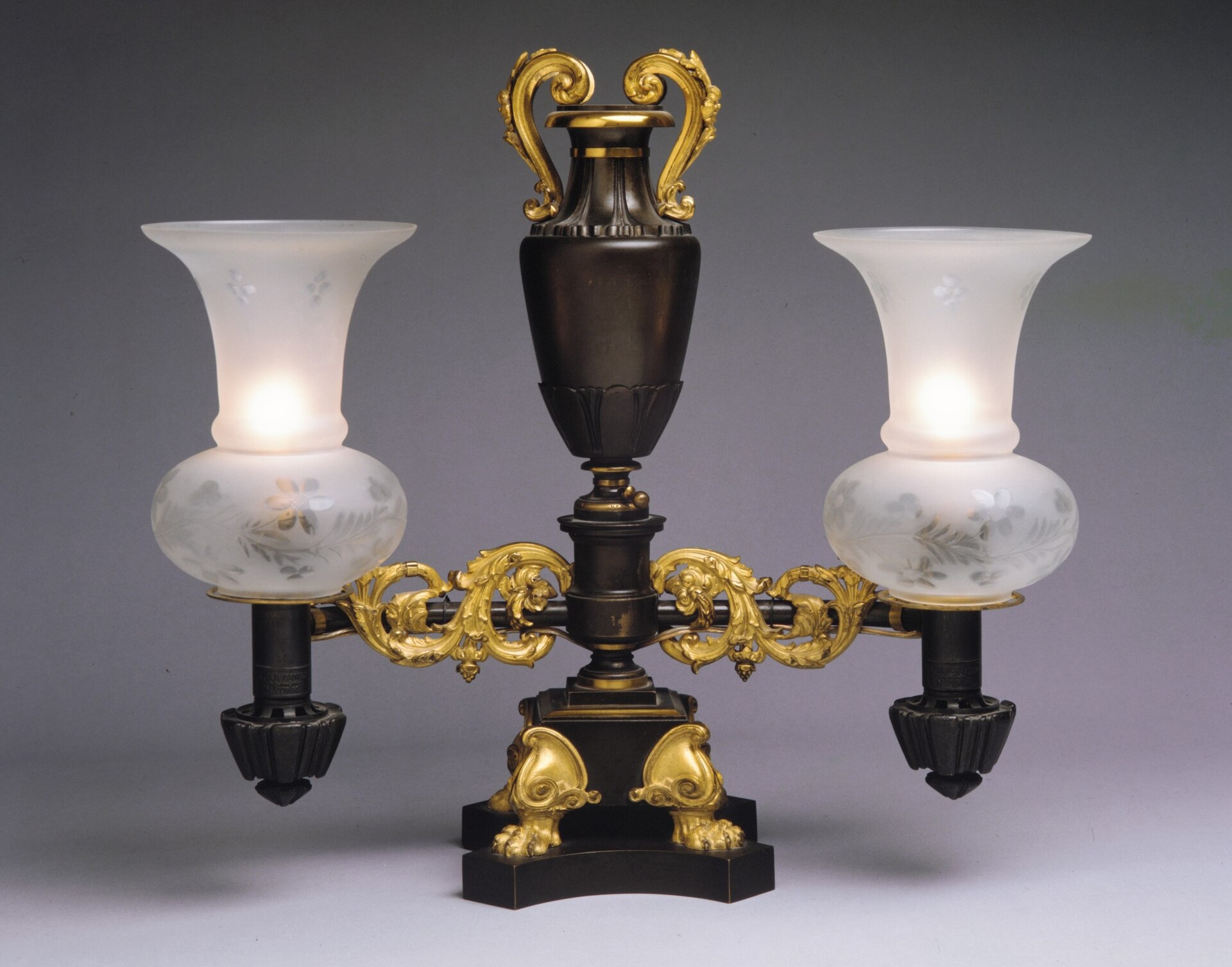A gilt-bronze Argand lamp of about 1835 with its circular-wick burner, glass chimney, and overhead oil reservoir