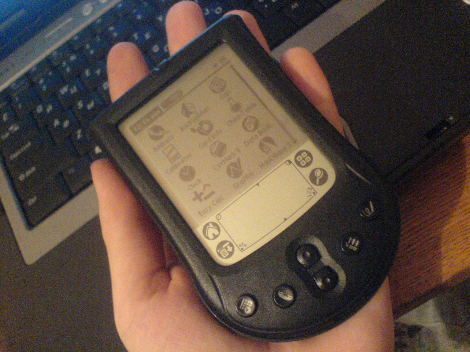 A Palm m125 PDA held in the hand, showing the touchscreen