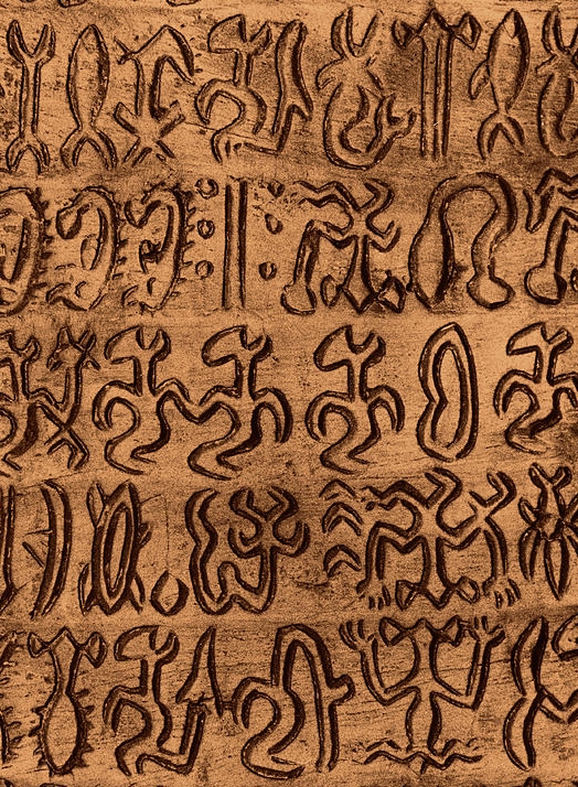 Close-up of a rongorongo tablet showing rows of incised glyphs written in reverse boustrophedon, with alternate lines inverted
