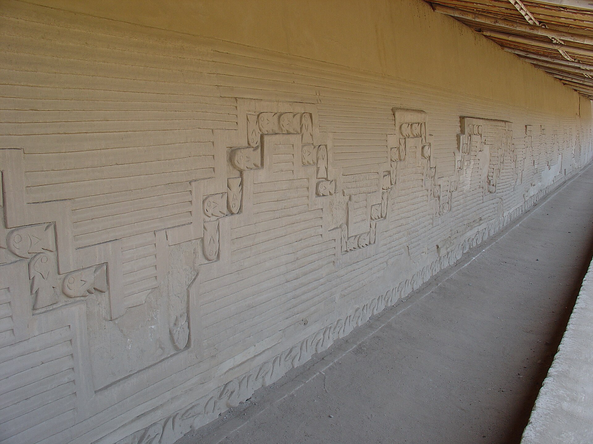 Carved adobe wall reliefs at Chan Chan, Peru — repeating geometric and animal motifs in mud brick